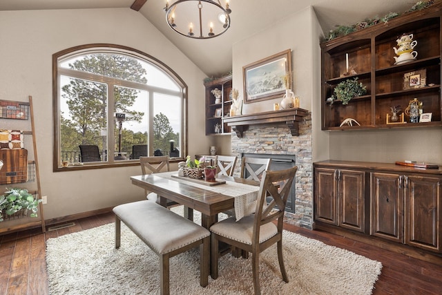 dining area featuring an inviting chandelier, a fireplace, dark wood-type flooring, and vaulted ceiling