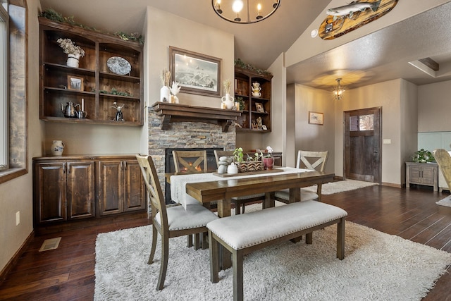 dining room with dark hardwood / wood-style flooring, a notable chandelier, and a fireplace