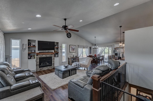 living room with lofted ceiling, a fireplace, dark hardwood / wood-style floors, a textured ceiling, and ceiling fan with notable chandelier