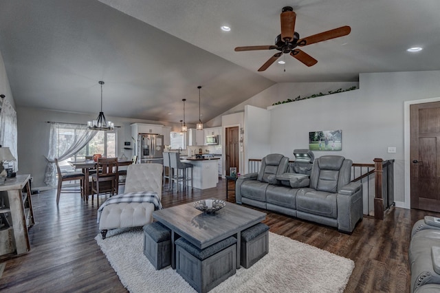 living room featuring vaulted ceiling, ceiling fan with notable chandelier, and dark hardwood / wood-style floors