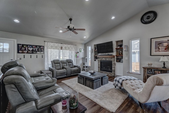 living room with hardwood / wood-style flooring, lofted ceiling, a stone fireplace, and a healthy amount of sunlight