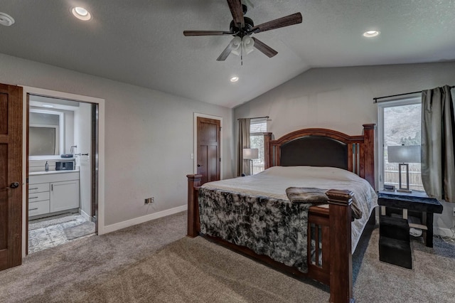 carpeted bedroom featuring ceiling fan, ensuite bath, multiple windows, and lofted ceiling