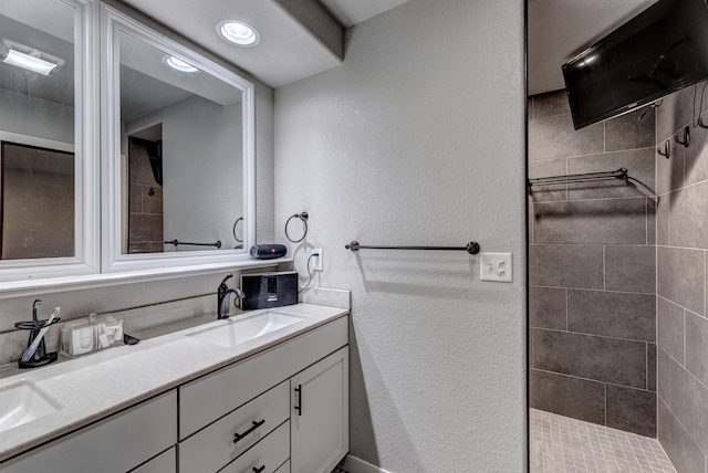 bathroom with a tile shower and vanity