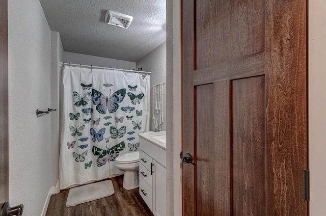 bathroom with hardwood / wood-style floors, a textured ceiling, vanity, toilet, and walk in shower