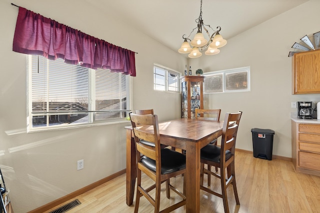 dining space with light hardwood / wood-style flooring and a chandelier