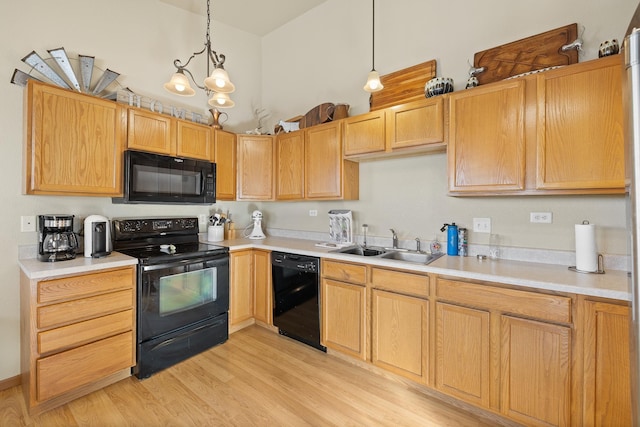 kitchen featuring black appliances, sink, light hardwood / wood-style flooring, hanging light fixtures, and a chandelier