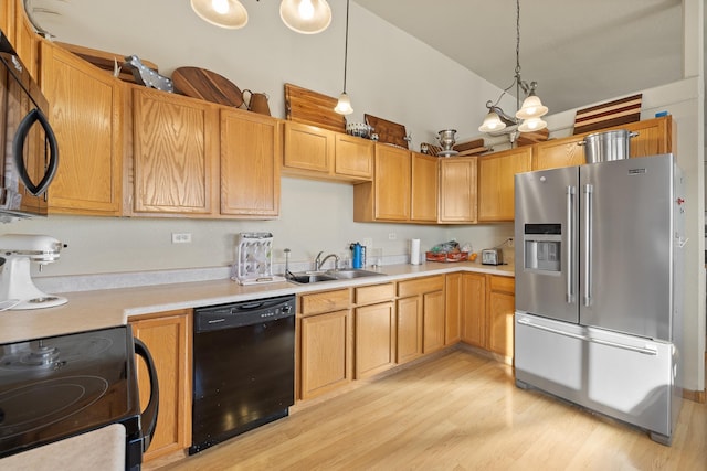 kitchen with decorative light fixtures, black appliances, sink, an inviting chandelier, and light hardwood / wood-style flooring