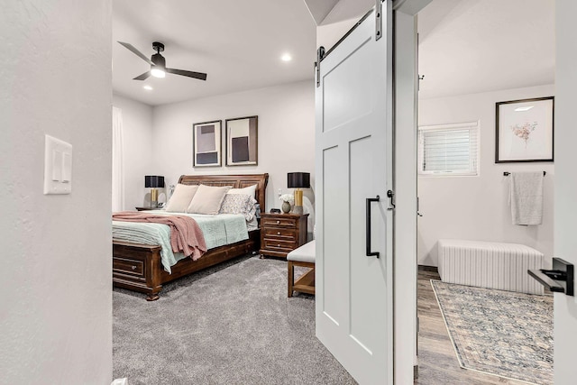 carpeted bedroom featuring ceiling fan and a barn door