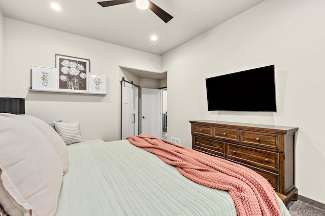 bedroom with ceiling fan and a barn door