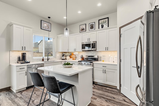 kitchen featuring a center island, pendant lighting, sink, stainless steel appliances, and white cabinets