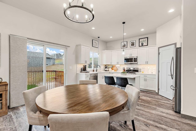 dining room featuring a notable chandelier, sink, and light hardwood / wood-style flooring