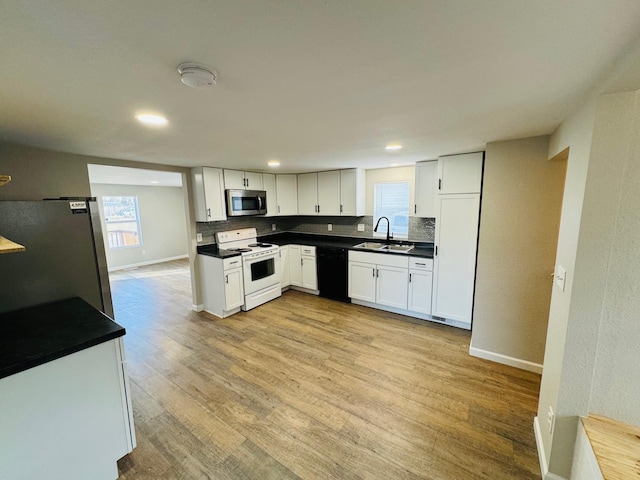 kitchen with backsplash, sink, white cabinetry, light wood-type flooring, and appliances with stainless steel finishes