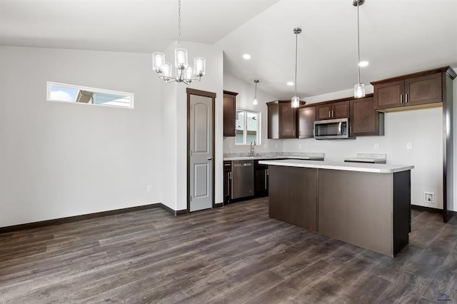 kitchen featuring decorative light fixtures, vaulted ceiling, a kitchen island, dark brown cabinetry, and appliances with stainless steel finishes