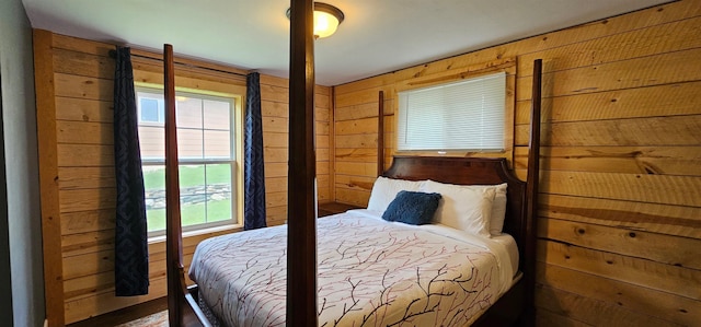 bedroom featuring wooden walls and multiple windows