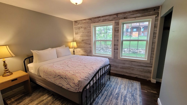 bedroom with wood walls and dark hardwood / wood-style floors