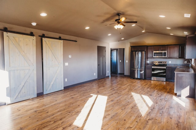 kitchen featuring light hardwood / wood-style floors, a barn door, and appliances with stainless steel finishes