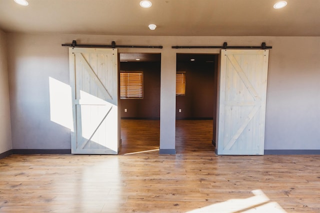 empty room featuring a barn door and light hardwood / wood-style flooring