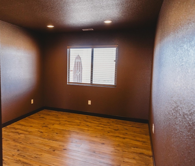 spare room with a textured ceiling and wood-type flooring