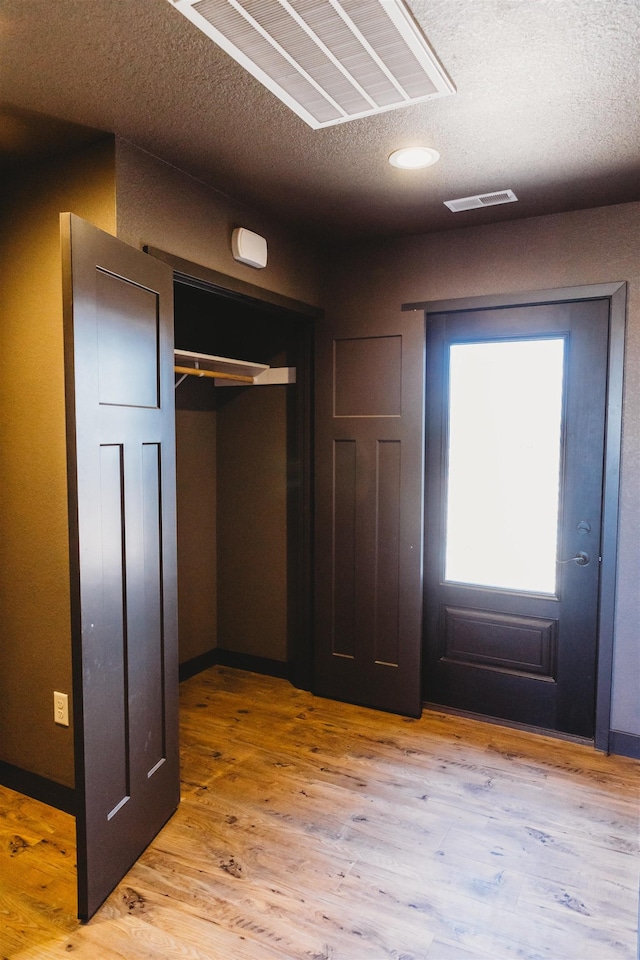 interior space with light wood-type flooring and a textured ceiling