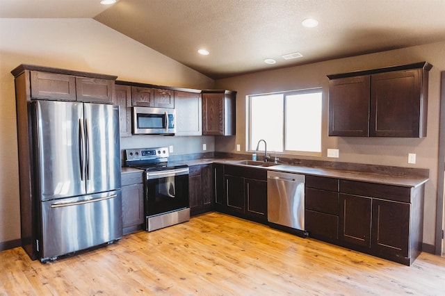 kitchen with lofted ceiling, stainless steel appliances, light hardwood / wood-style floors, sink, and dark brown cabinets