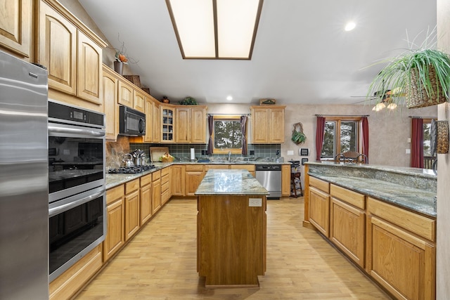 kitchen featuring light stone counters, a wealth of natural light, appliances with stainless steel finishes, and a kitchen island