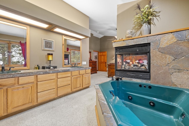 bathroom featuring vanity, a tub to relax in, lofted ceiling, and a multi sided fireplace