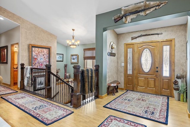 entrance foyer featuring hardwood / wood-style flooring, lofted ceiling, and a notable chandelier