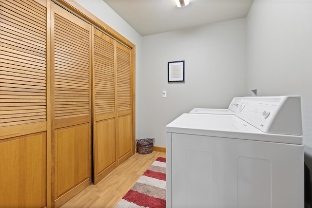 laundry room with separate washer and dryer and light hardwood / wood-style floors