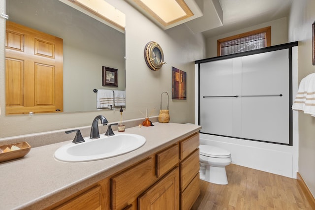 full bathroom featuring toilet, vanity, bath / shower combo with glass door, and hardwood / wood-style flooring