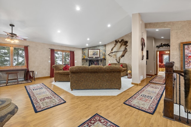 living room featuring ceiling fan, light wood-type flooring, and lofted ceiling