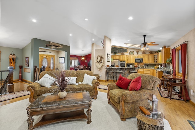 living room with lofted ceiling, light hardwood / wood-style floors, and ceiling fan