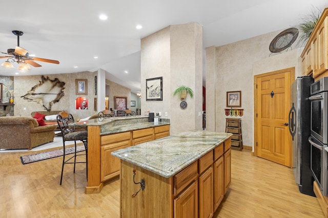 kitchen with lofted ceiling, a kitchen breakfast bar, a center island, kitchen peninsula, and light wood-type flooring