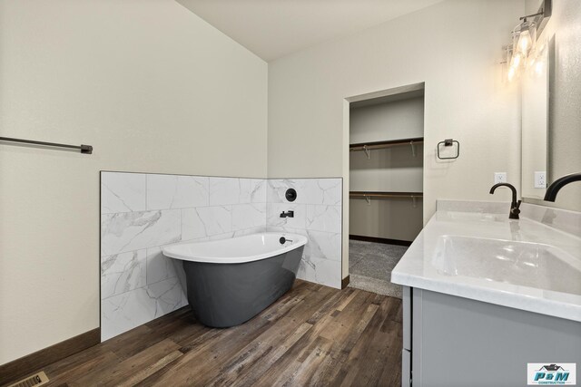 bathroom with vanity, a tub to relax in, and wood-type flooring