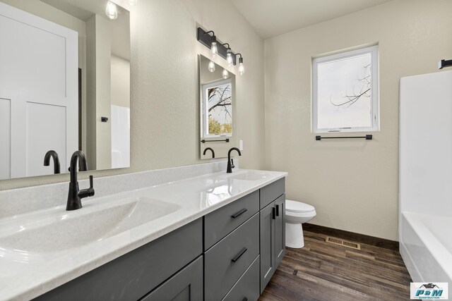 bathroom with vanity, toilet, hardwood / wood-style floors, and a bathtub