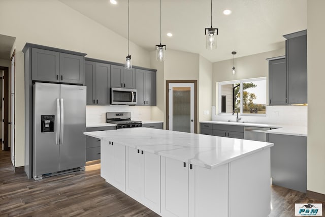 kitchen featuring pendant lighting, a kitchen island, appliances with stainless steel finishes, and tasteful backsplash