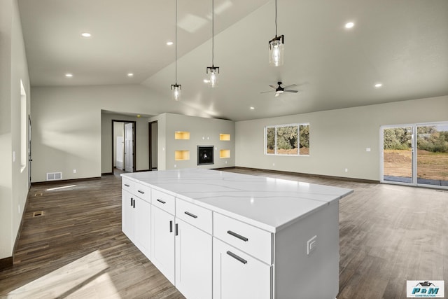 kitchen with pendant lighting, a large island, white cabinetry, light stone countertops, and lofted ceiling