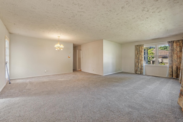 unfurnished room with a textured ceiling, a notable chandelier, and carpet