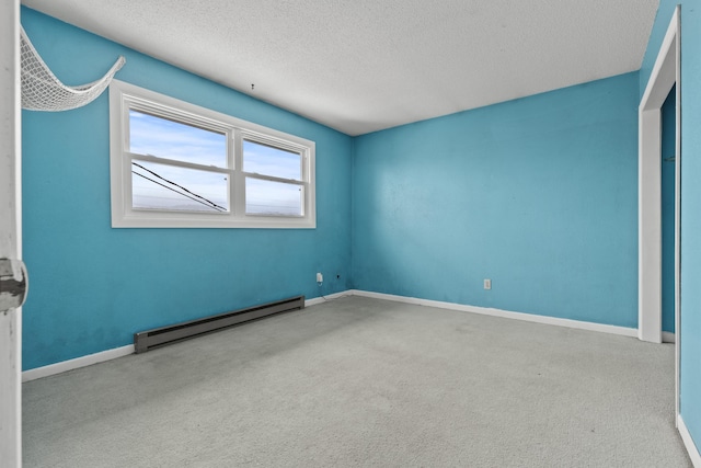 carpeted spare room featuring baseboard heating and a textured ceiling