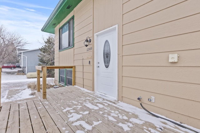 snow covered property entrance with a deck