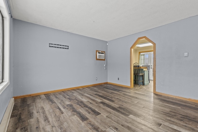 spare room featuring wood-type flooring, a baseboard heating unit, and a wall mounted AC