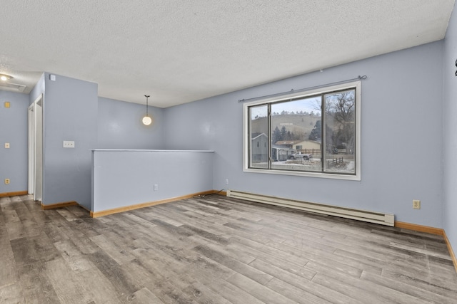 unfurnished room with wood-type flooring, a baseboard radiator, and a textured ceiling