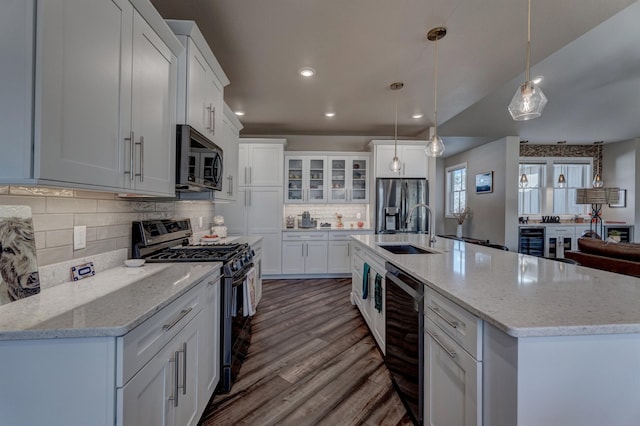 kitchen featuring stainless steel appliances, hanging light fixtures, sink, and white cabinets