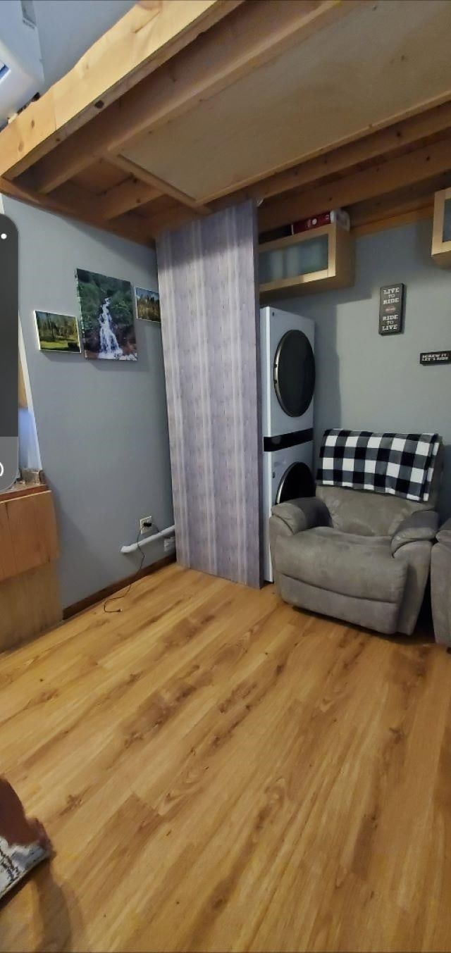 basement with hardwood / wood-style flooring and stacked washer and clothes dryer