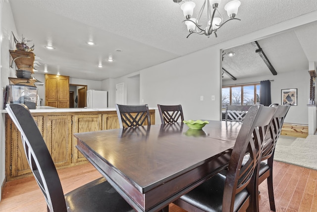 dining area featuring a chandelier, a textured ceiling, and light wood-type flooring