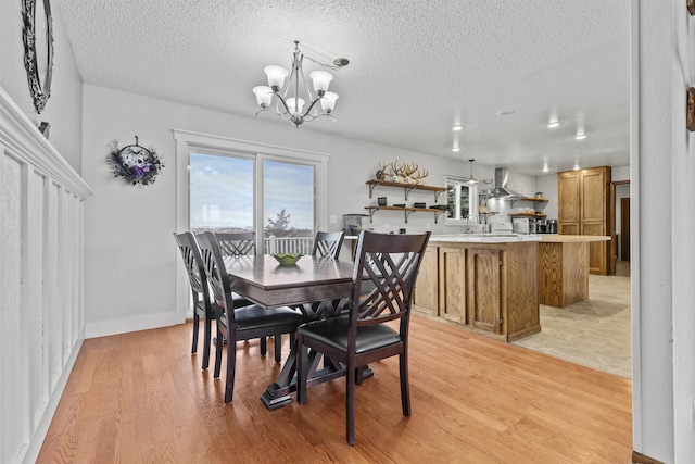 dining space with a chandelier, a textured ceiling, and light wood-type flooring