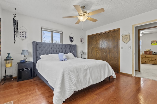 bedroom featuring hardwood / wood-style flooring, ceiling fan, a closet, and a textured ceiling