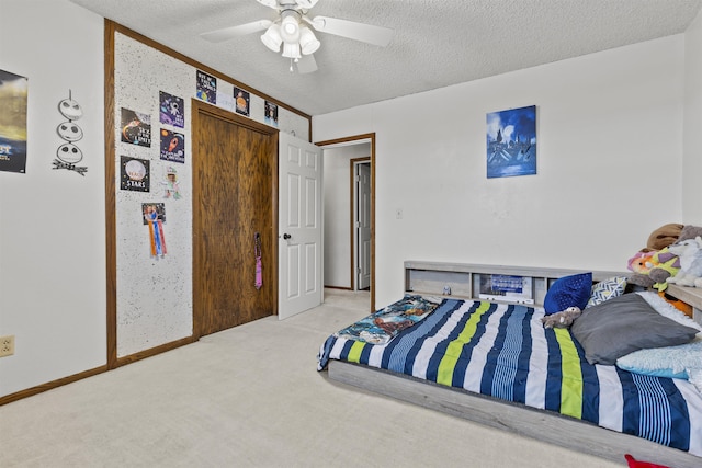 carpeted bedroom featuring ceiling fan and a textured ceiling