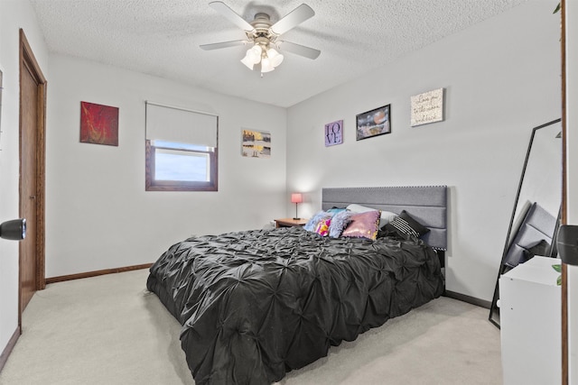 bedroom with ceiling fan, light colored carpet, and a textured ceiling