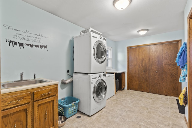 laundry room with cabinets, stacked washer / drying machine, and sink