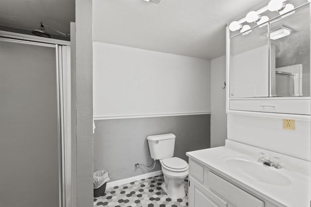 bathroom with vanity, toilet, and a shower with door